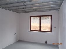 Omítnutá místnost s dřevěným oknem, strop bez podhledu