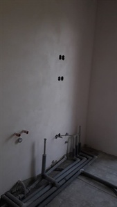Omítnutá stěna s vývody instalace u podlahy