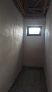 Rozestavěná úzká chodba s malým oknem na konci